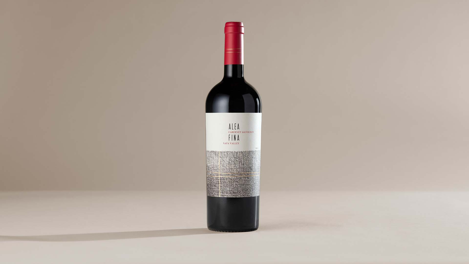 A bottle of Alea Fina wine centred on a light beige backdrop.